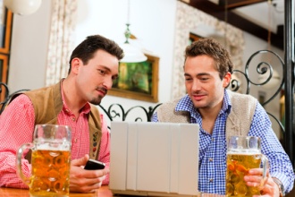 Zwei Freunde in bayerischer Wirtschaft mit Laptop